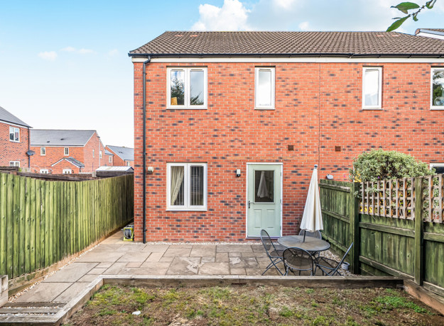 Rear garden with paved patio, outdoor seating and fenced boundaries.