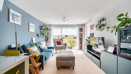 Living room with sofa, footstool, shelving unit and large window.