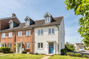 Row of modern terraced houses with brick and cream facades and a small front lawn.