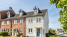 Row of modern terraced houses with brick and cream facades and a small front lawn.