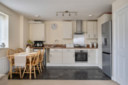 Open plan kitchen and dining area with table, chairs, appliances and fitted cabinets.