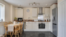 Open plan kitchen and dining area with table, chairs, appliances and fitted cabinets.