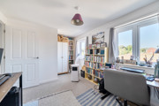 Home office with desk, shelving unit and large window.