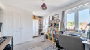 Home office with desk, shelving unit and large window.