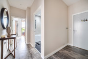 Entry hall with wooden flooring, leading into rooms and bathroom.