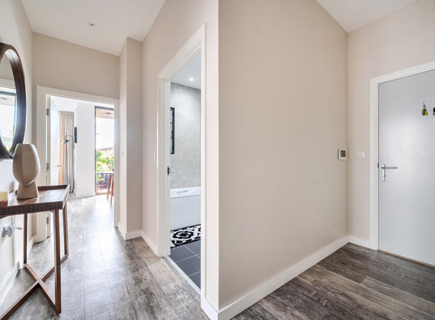 Entry hall with wooden flooring, leading into rooms and bathroom.