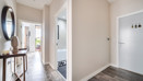 Entry hall with wooden flooring, leading into rooms and bathroom.
