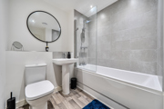 Bathroom with bathtub, shower screen, toilet and wash basin.