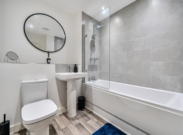 Bathroom with bathtub, shower screen, toilet and wash basin.