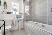 Bathroom with bathtub, sink, toilet, and window.