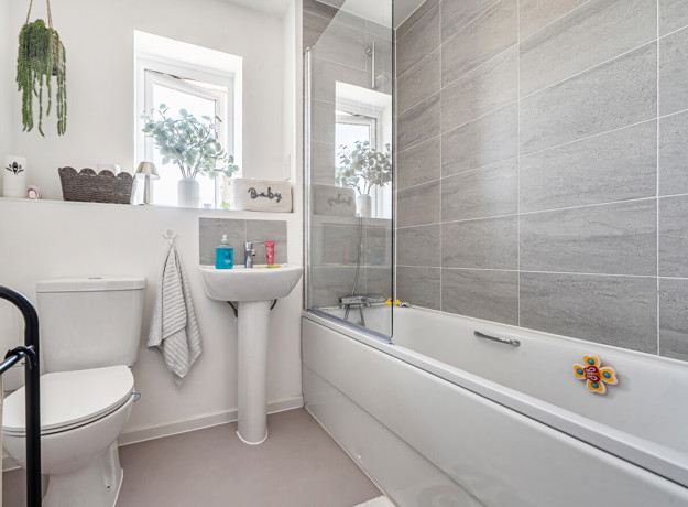 Bathroom with bathtub, sink, toilet, and window.