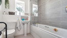 Bathroom with bathtub, sink, toilet, and window.