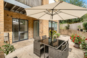 Patio with outdoor seating, parasol and potted plants.