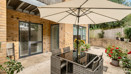 Patio with outdoor seating, parasol and potted plants.