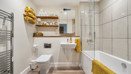 Bathroom with a bathtub, shower enclosure, toilet and wall-mounted shelves.