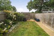 Garden with lawn, paved path, fencing and planted borders along the edges.