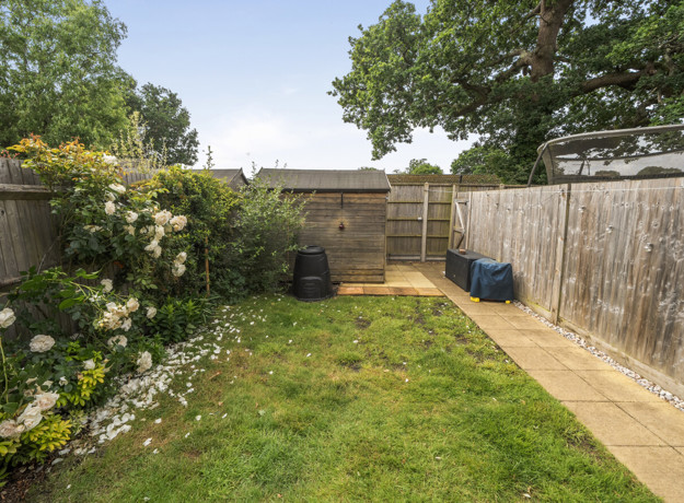 Garden with lawn, paved path, fencing and planted borders along the edges.