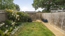 Garden with lawn, paved path, fencing and planted borders along the edges.