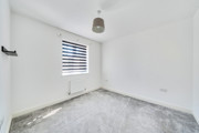 Empty bedroom with grey carpet and window with blind.