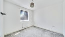 Empty bedroom with grey carpet and window with blind.