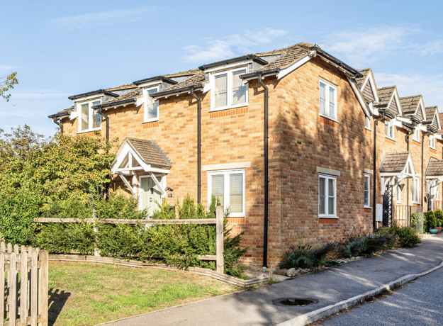 Brick end-of-terrace house with parking area and landscaped frontage.