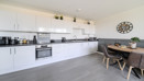 Open-plan kitchen with fitted units, dining table and seating area.