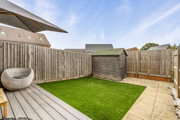 Enclosed rear garden with lawn, decking and storage shed.