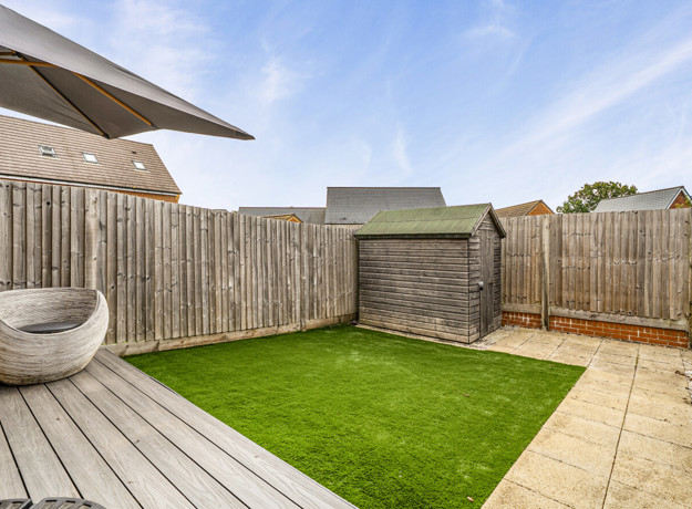Enclosed rear garden with lawn, decking and storage shed.