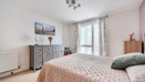 Bedroom with double bed, chest of drawers and window with curtains.