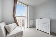 Balcony view from living area with armchair, chest of drawers and radiator.