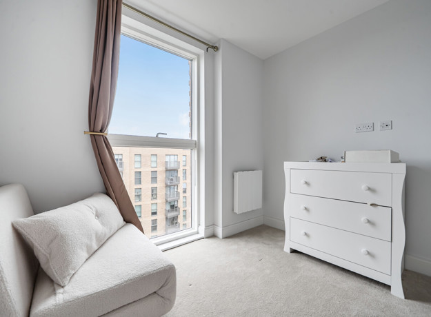 Balcony view from living area with armchair, chest of drawers and radiator.