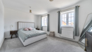 Bedroom with double bed, bedside table and two windows with curtains.