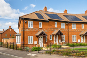Row of red-brick terraced houses with front gardens and solar panels on roofs. (1)