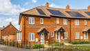 Row of red-brick terraced houses with front gardens and solar panels on roofs. (1)