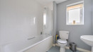 Bathroom with bathtub, toilet, sink, and frosted window .