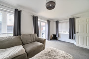 Living room with sofa, multiple windows, patio doors and carpeted flooring.