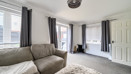 Living room with sofa, multiple windows, patio doors and carpeted flooring.