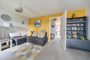 Living room with grey sofa, shelving unit and yellow feature wall.