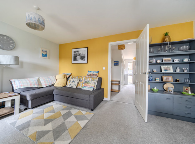 Living room with grey sofa, shelving unit and yellow feature wall.