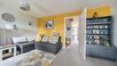 Living room with grey sofa, shelving unit and yellow feature wall.