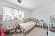 Child's bedroom with a bed, window, rug and toys.