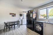Dining and kitchen area with table, appliances, window and door into garden.