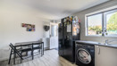 Dining and kitchen area with table, appliances, window and door into garden.