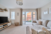 Living room with sofas, TV unit and doors leading to a balcony.