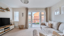 Living room with sofas, TV unit and doors leading to a balcony.