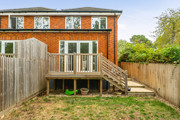 Rear view of the house with a raised wooden deck and steps to the garden.