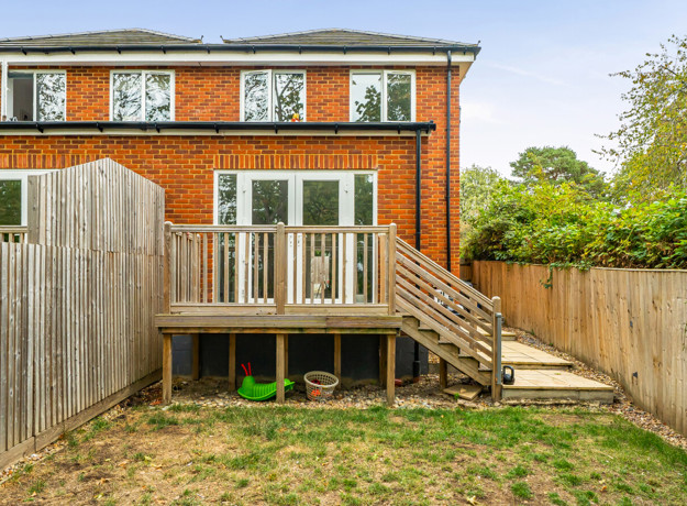 Rear view of the house with a raised wooden deck and steps to the garden.