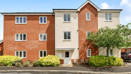 Brick apartment building with shrubs, lawn, and paved walkway at front.