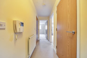 Hallway with intercom, wooden doors and carpeted floor.