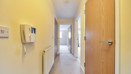 Hallway with intercom, wooden doors and carpeted floor.